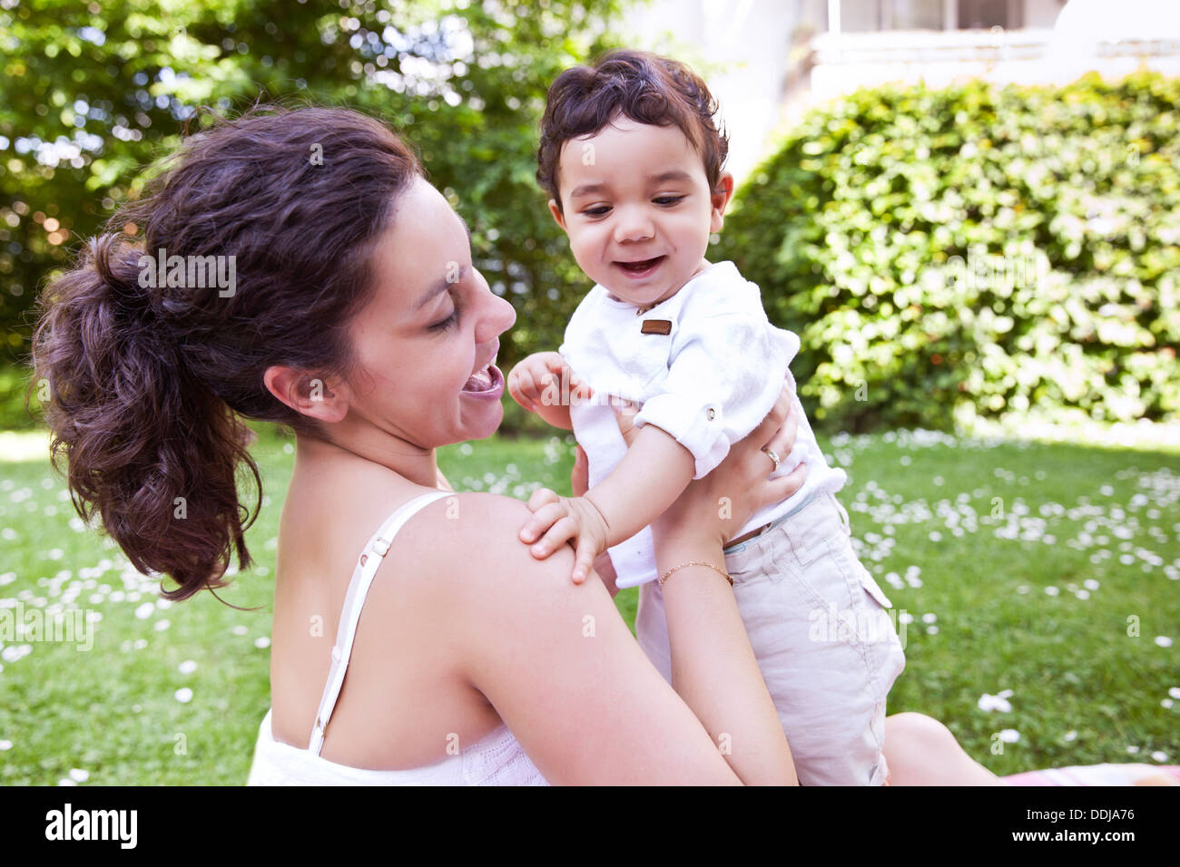 Mère de câliner son bébé garçon sur l'herbe, smiling Banque D'Images