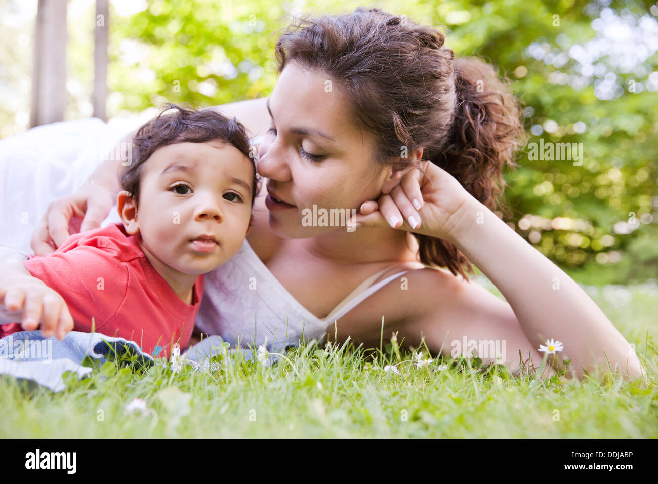Mère de câliner son bébé garçon sur l'herbe Banque D'Images