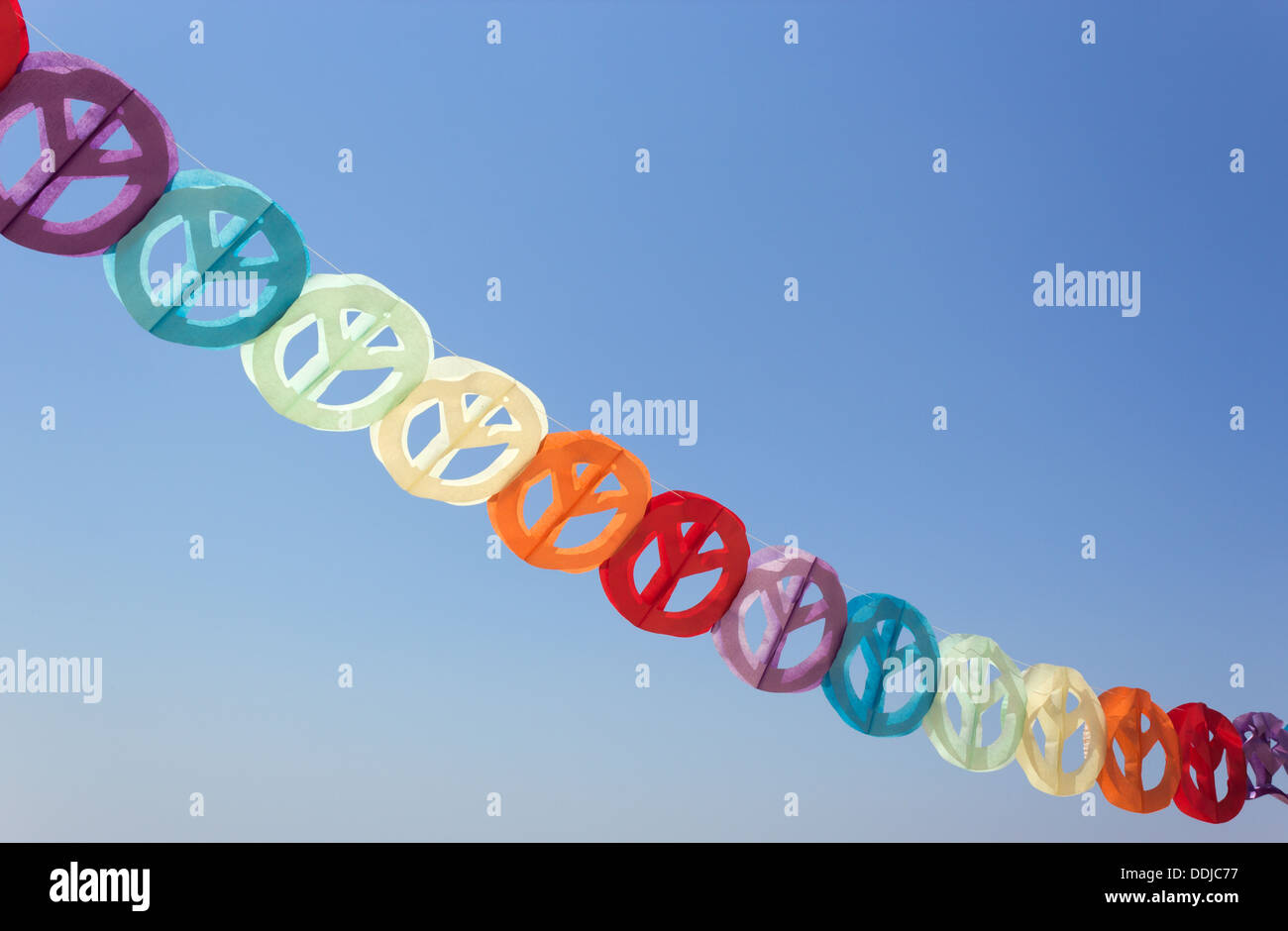 Guirlande papier coloré de signes de paix contre le ciel bleu. Banque D'Images