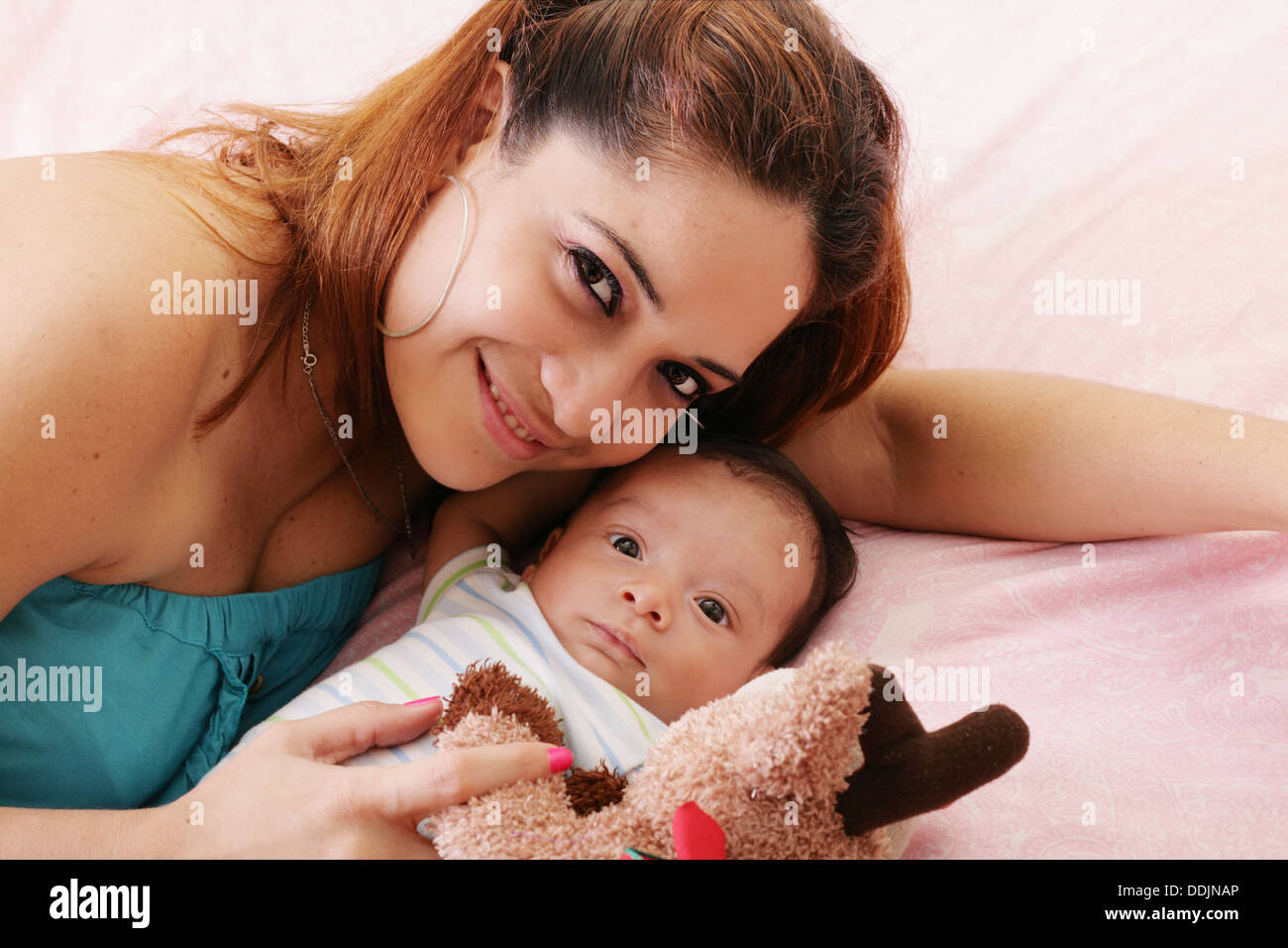Heureuse maman et bébé boy smiling in le lit teddy bear Banque D'Images
