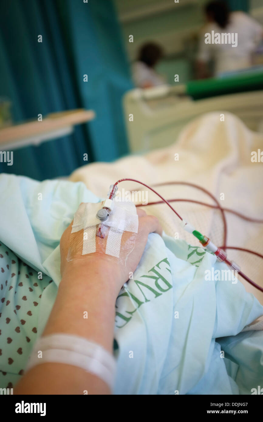 Une femme d'âge moyen de recevoir une transfusion sanguine dans un lit d'hôpital après une opération un remplacement de la hanche, NHS Hospital, Royaume-Uni Banque D'Images