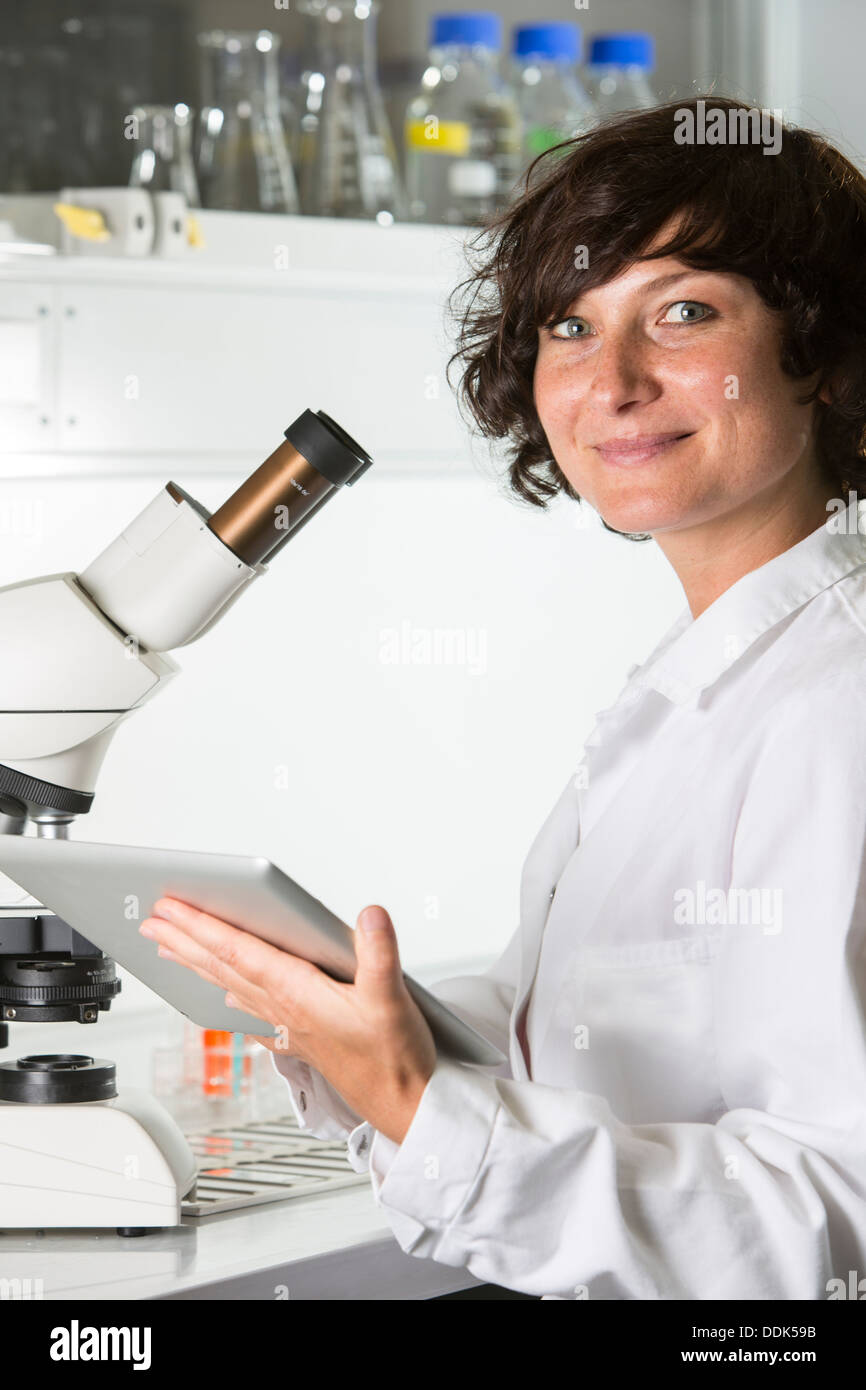 Chercheur scientifique au laboratoire avec microscope et tablet computer Banque D'Images