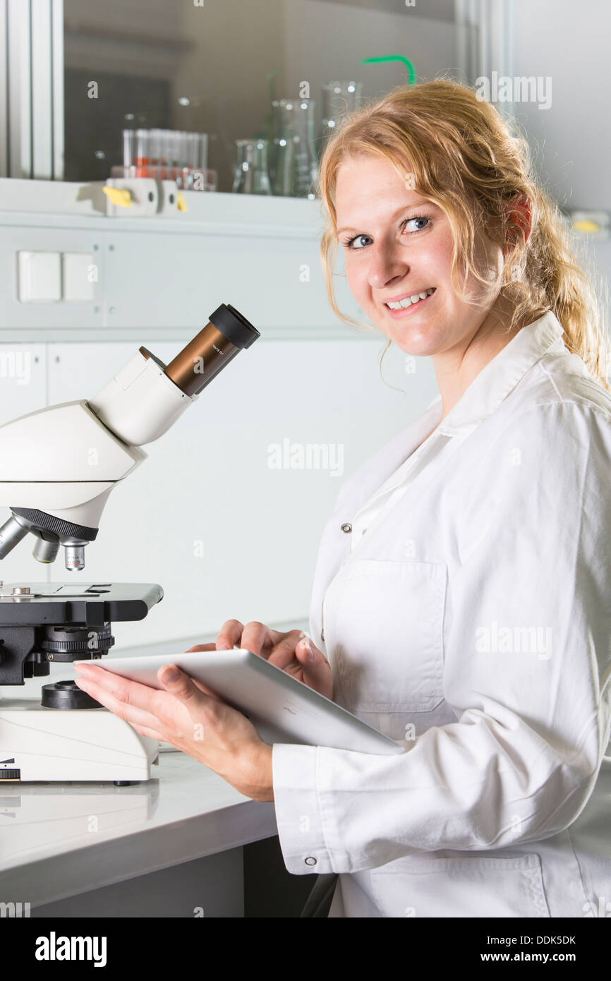 Female scientist au laboratoire avec microscope et tablet computer Banque D'Images