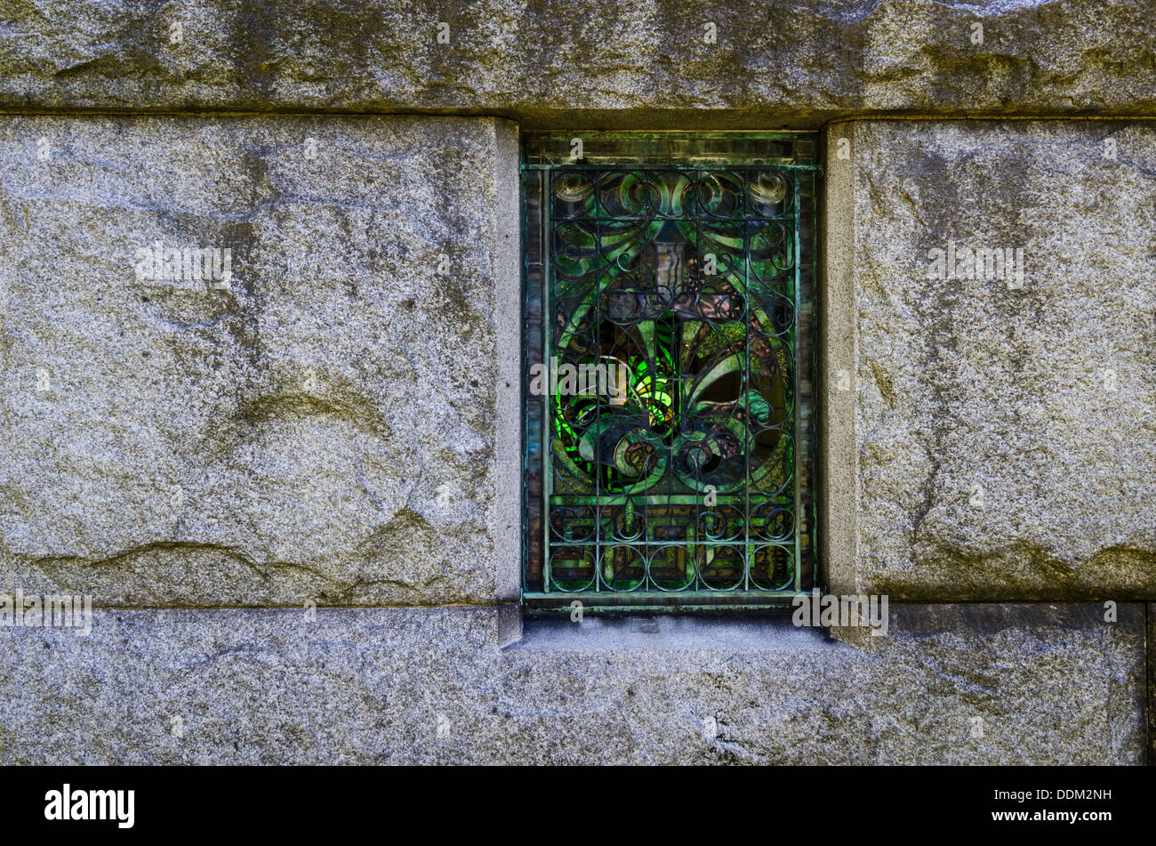 Fenêtre cassée dans un mausolée avec des volutes en fer forgé et vitraux décoratifs. Banque D'Images