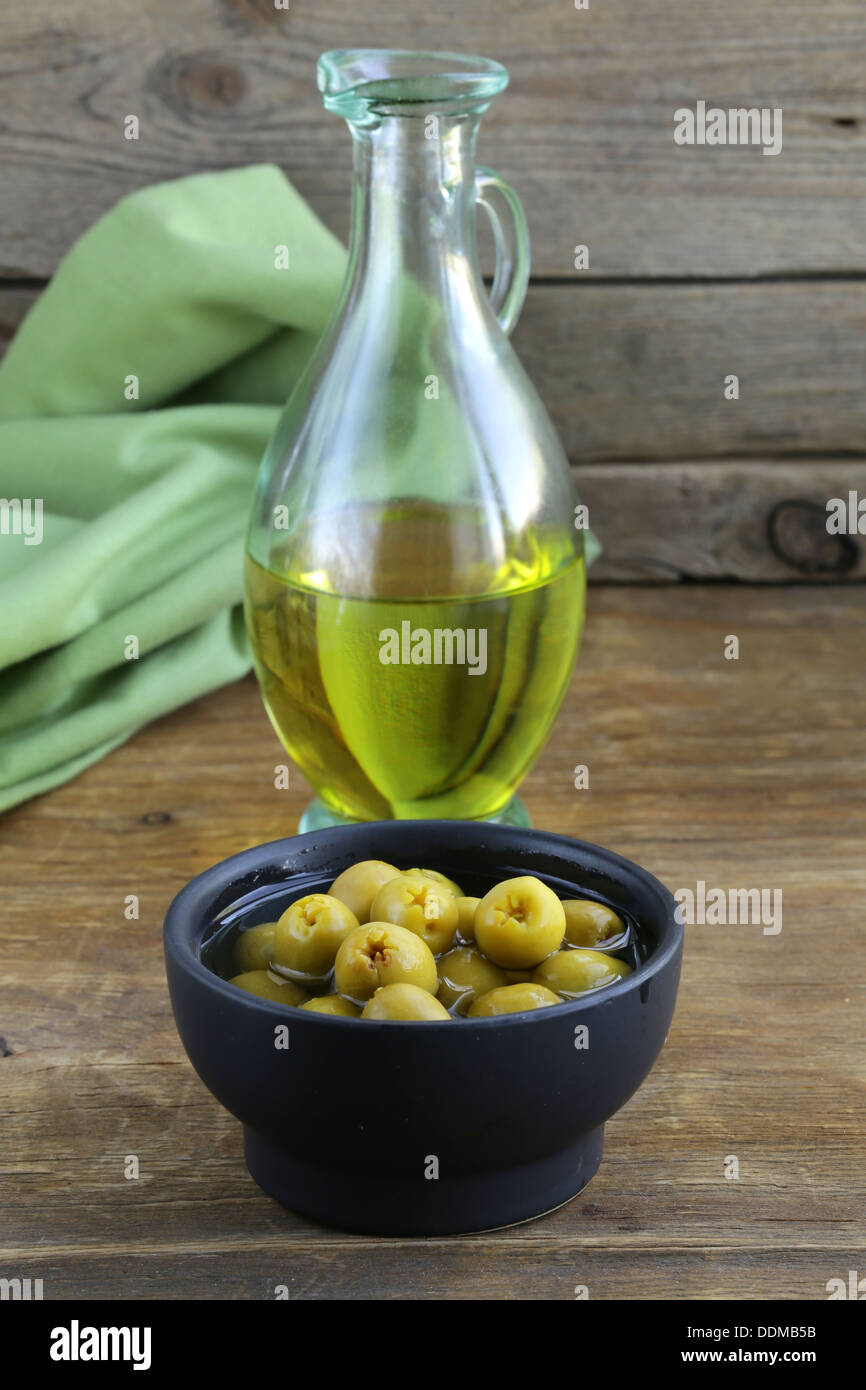 Olives vertes marinées et une bouteille d'huile sur table en bois Banque D'Images