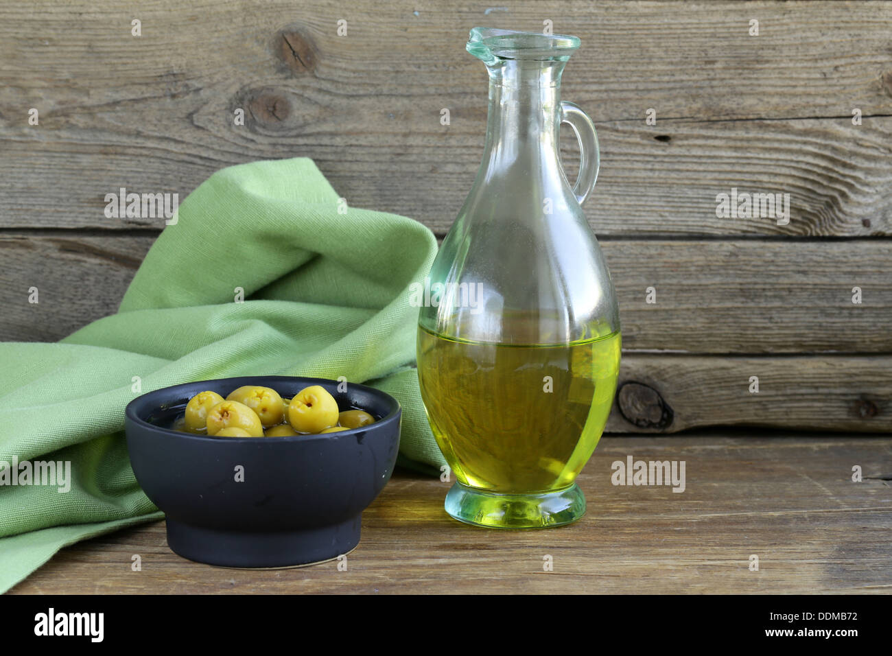 Olives vertes marinées et une bouteille d'huile sur table en bois Banque D'Images