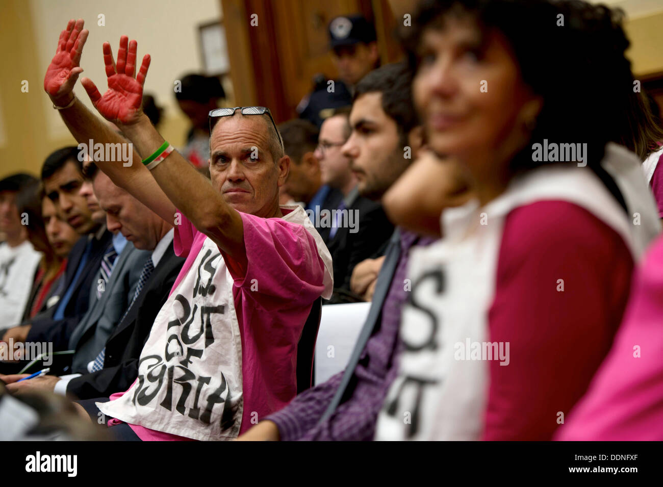 Un manifestant avec code rose lève les mains de couleur avec l'encre rouge au cours d'une audience sur la Syrie avant la commission des affaires étrangères de la Chambre le 4 septembre 2013 à Washington DC. Au cours de l'audience, Kerry, Hagel et chef de l'état-major général Martin Dempsey a discuté une possible intervention militaire en réponse à l'utilisation d'armes chimiques par la Syrie sur leur propre peuple. Banque D'Images