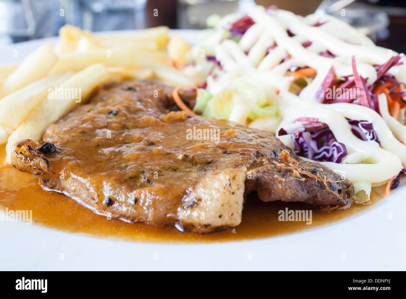 Escalope de porc avec frites et salade sur une assiette blanche. Banque D'Images
