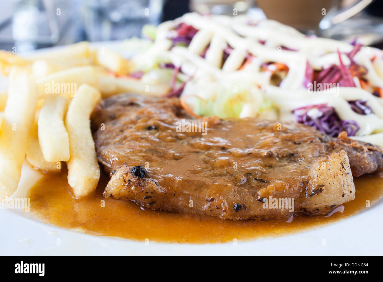Escalope de porc avec frites et salade sur une assiette blanche. Banque D'Images