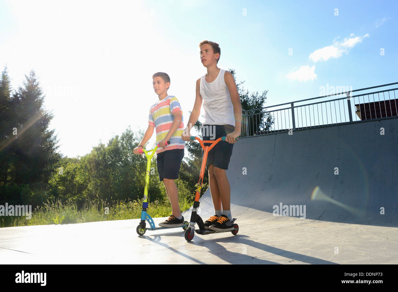 Deux garçons avec des scooters sur une place de sport Banque D'Images