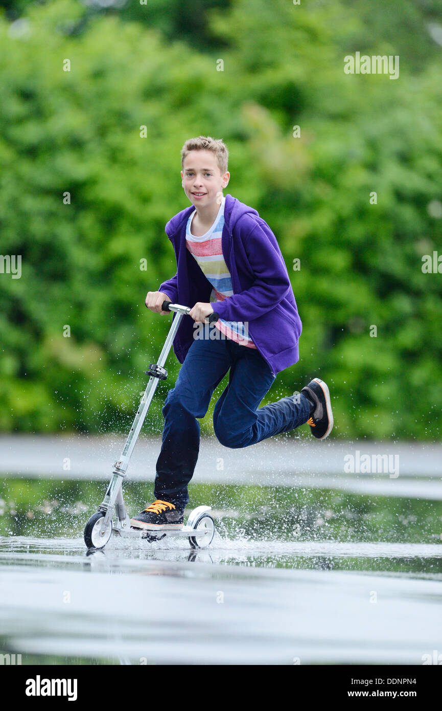 Garçon avec un scooter un jour de pluie Banque D'Images