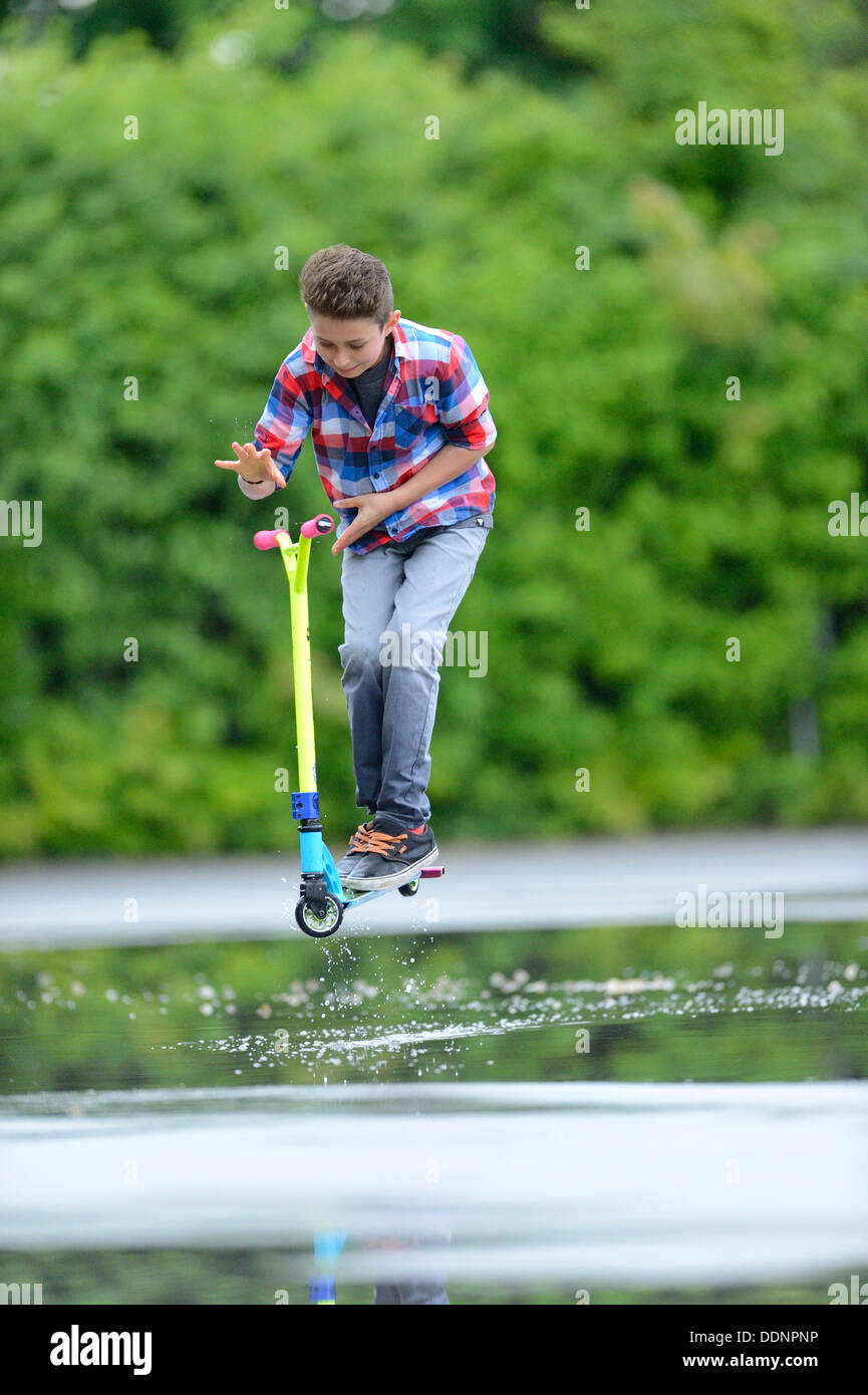 Garçon avec un scooter un jour de pluie Banque D'Images