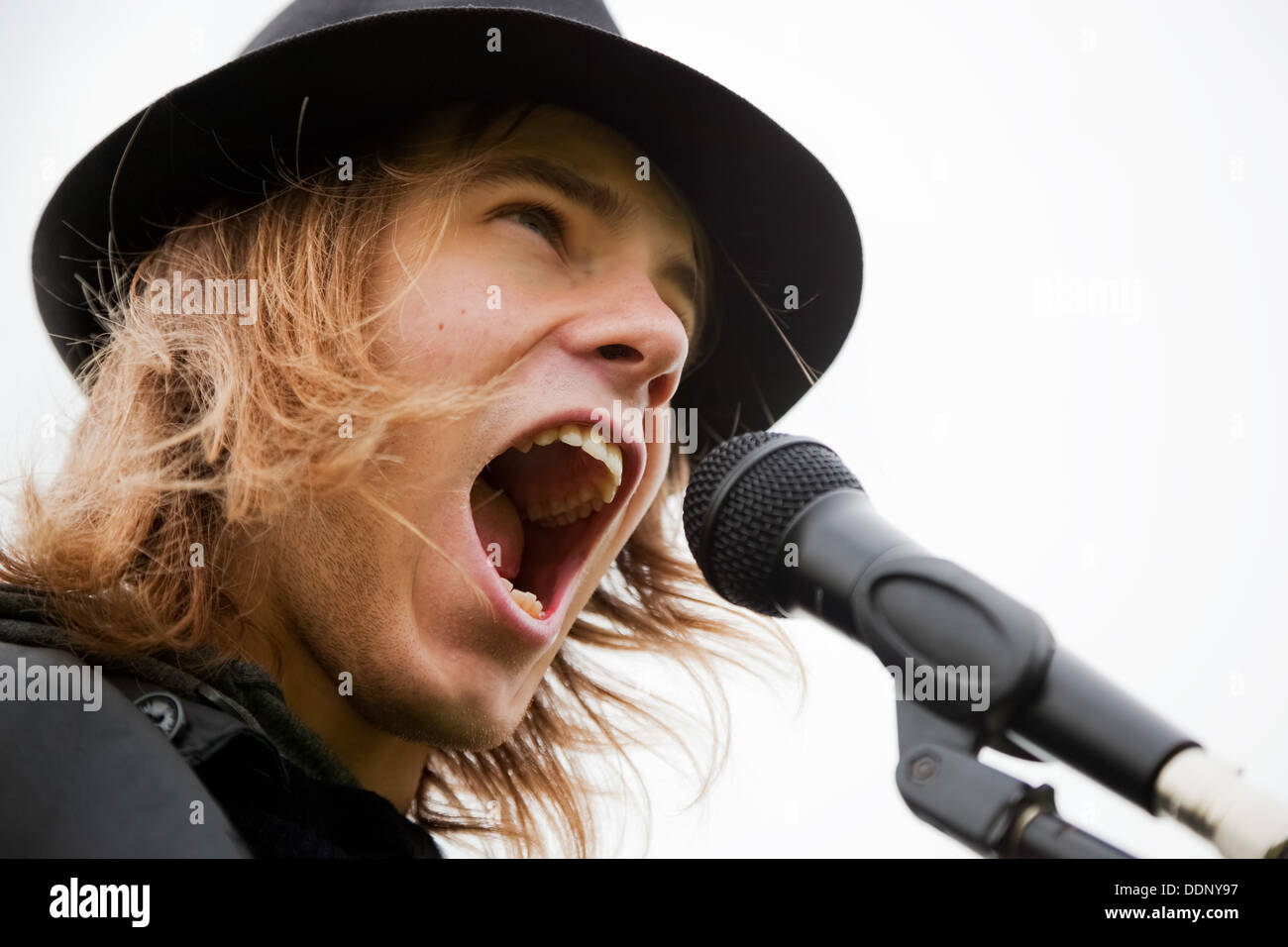 Young man in hat chante pour microphone Banque D'Images