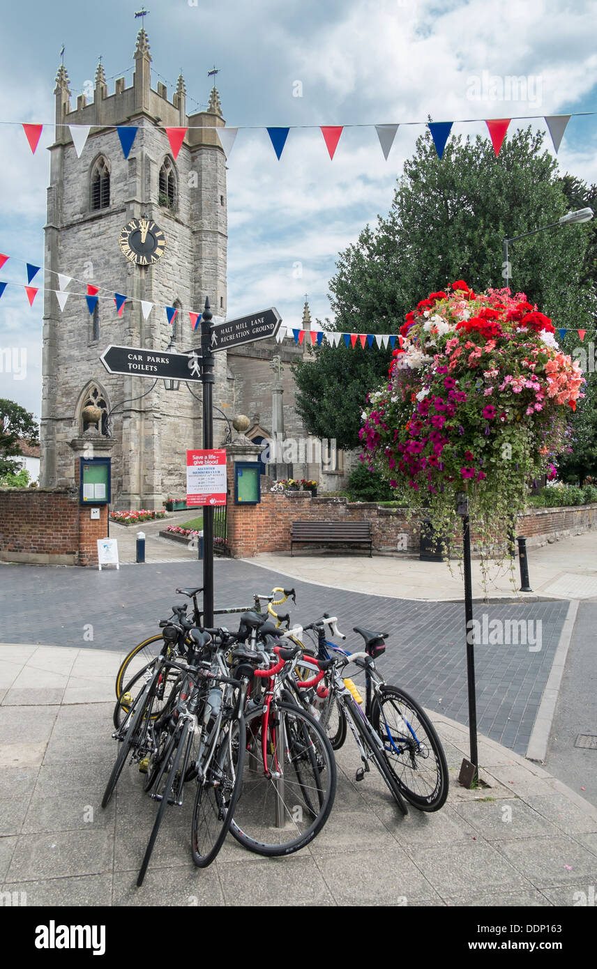 Bicyclettes reposant contre un doigt post dans High Street, Alcester Warwickshire avec St Nicholas church dans l'arrière du terrain. Banque D'Images