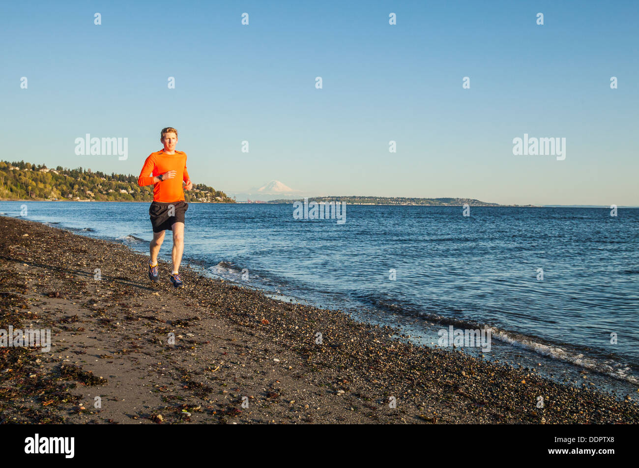 Un jeune homme qui court sur une plage de Discovery Park, Seattle, Washington, USA. Banque D'Images