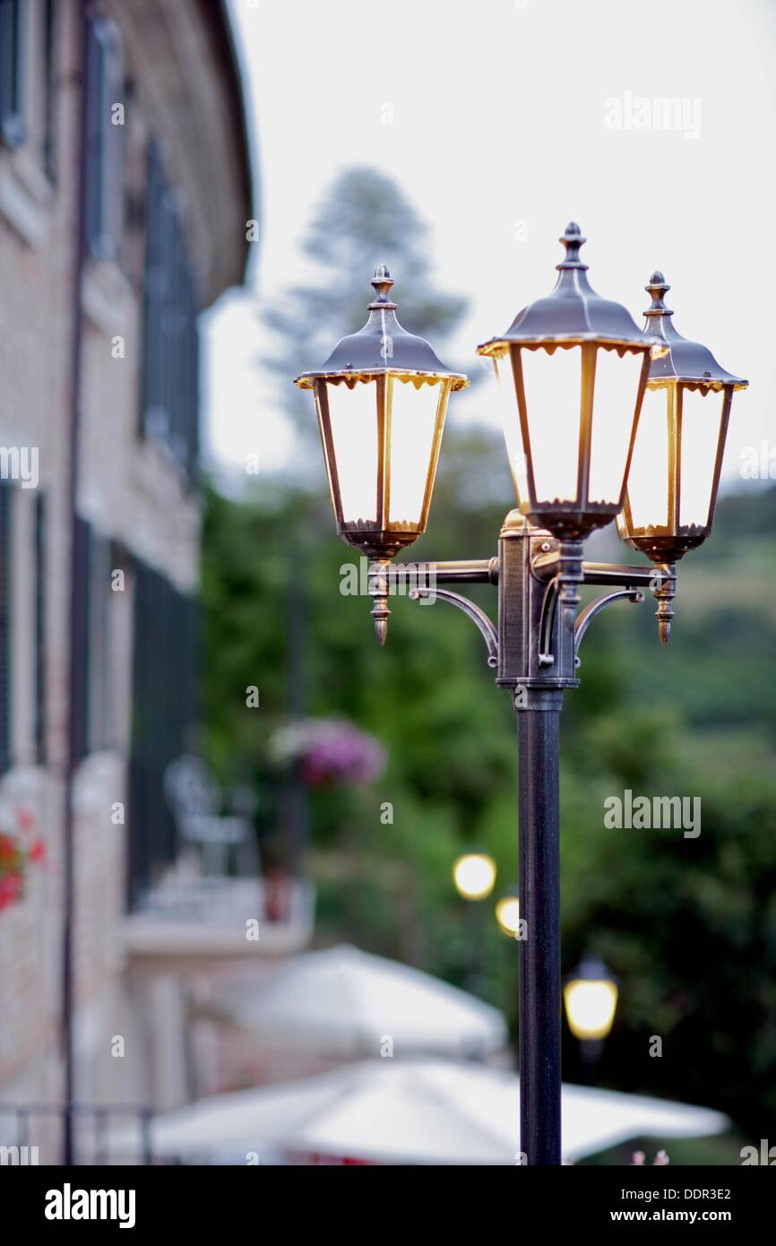 Burning lampe de rue avec trois laterns avec une maison, Gabiano, Pimont, Italie, Europe Banque D'Images