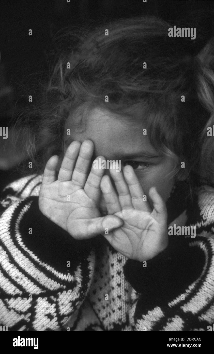 Triste petite fille appuyant ses mains contre la vitre Banque D'Images