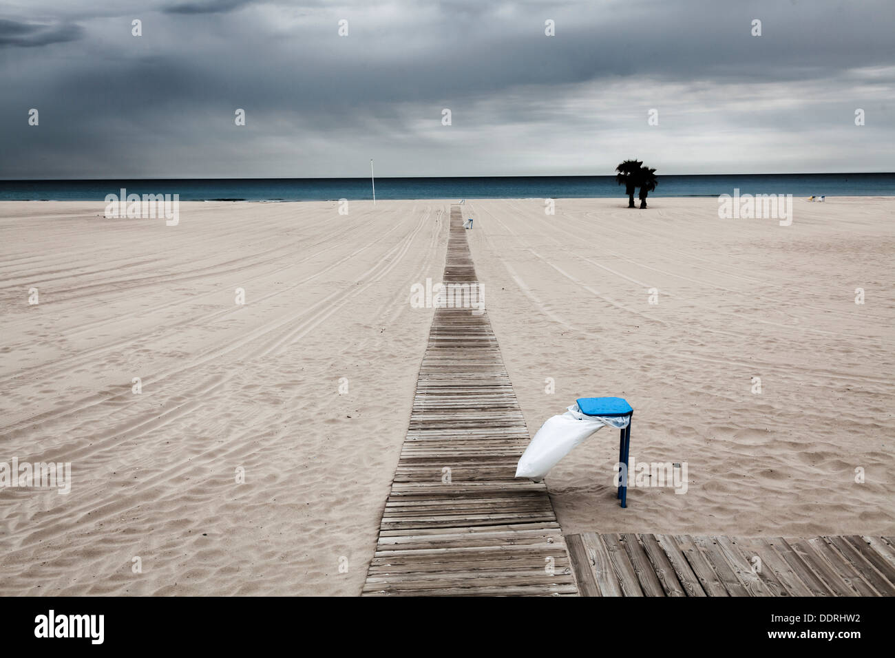 Plage vide sous un ciel couvert jour venteux avec poubelle Banque D'Images