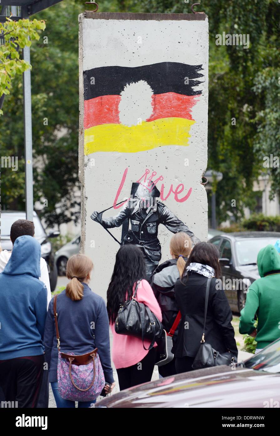 Les adolescents d'oeil à un morceau du Mur de Berlin avec une RDA flagg sur elle et une photo de l'garde-frontière Conrad Schumann, Berlin, Allemagne, 02 septembre 2013. Photo : Jens Kalaene Banque D'Images