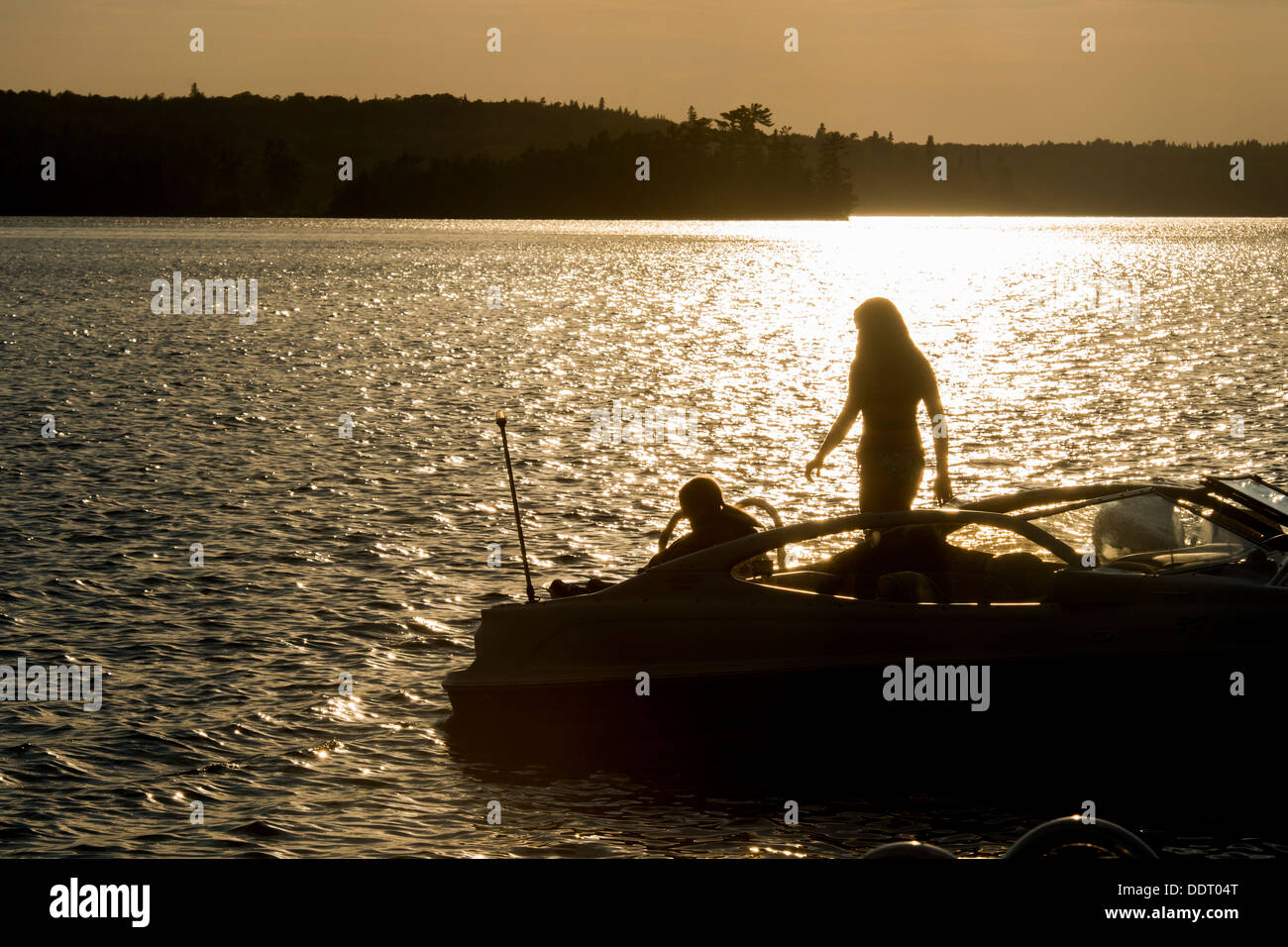 Silhouette de deux personnes sur un bateau au coucher du soleil, le lac des Bois, Keewatin (Ontario), Canada Banque D'Images