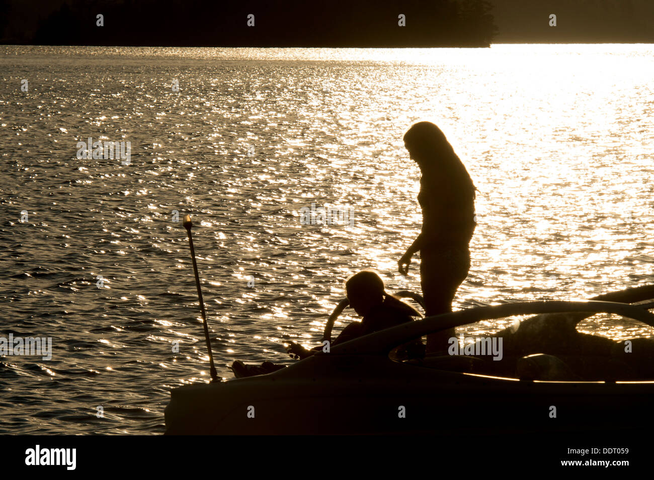 Silhouette de deux personnes sur un bateau au coucher du soleil, le lac des Bois, Keewatin (Ontario), Canada Banque D'Images