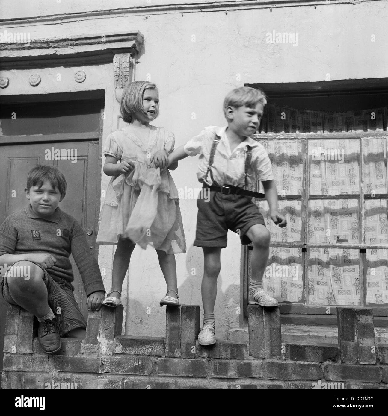 Enfants jouant sur un mur, Londres, 1960-1965. Artiste : John Gay Banque D'Images