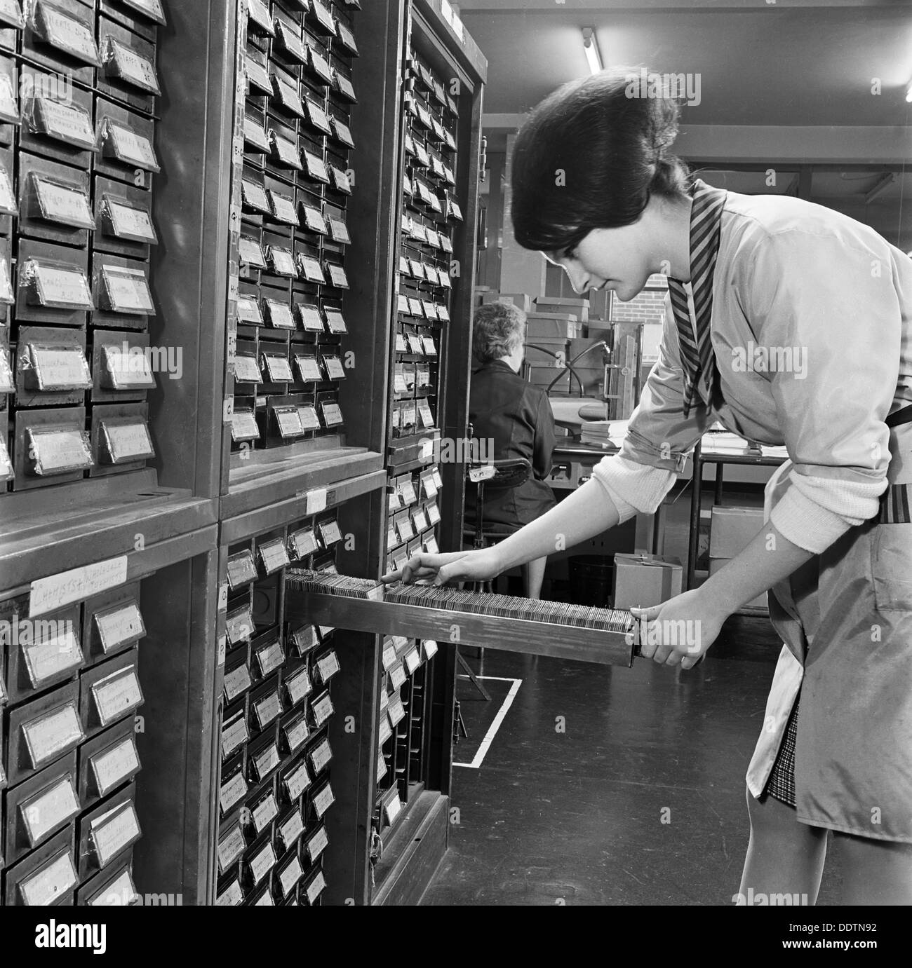 Femme regardant à travers des cartes, Société de diffusion médicale, Ealing, Londres, 1960-1970. Artiste : John Gay Banque D'Images