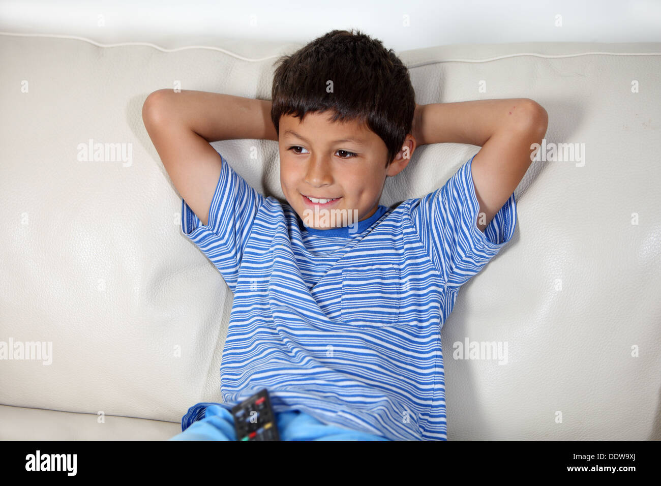 Jeune garçon regardant la TV avec télécommande Banque D'Images