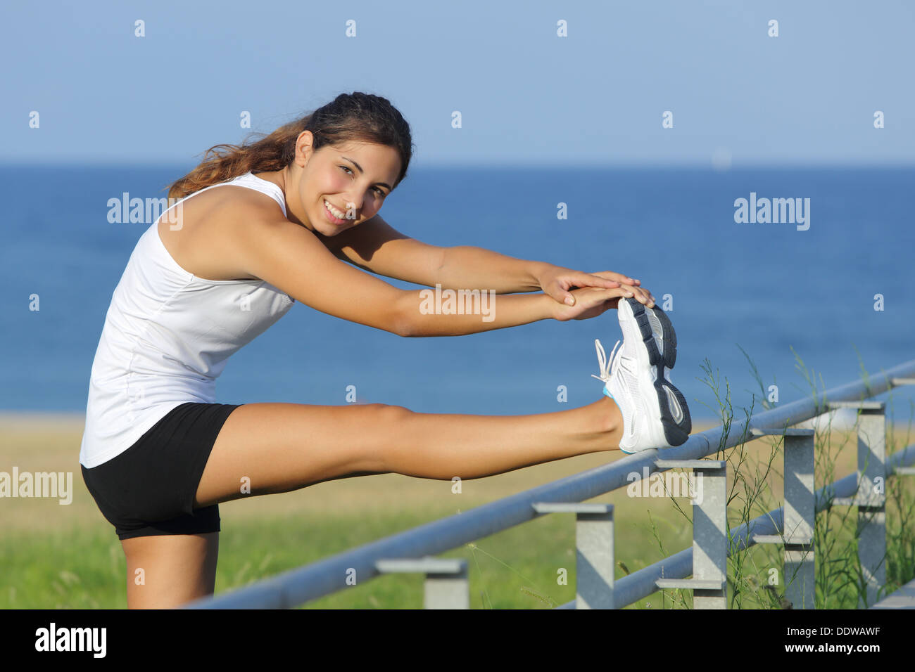 Belle femme de l'étirement des jambes avec la mer en arrière-plan Banque D'Images