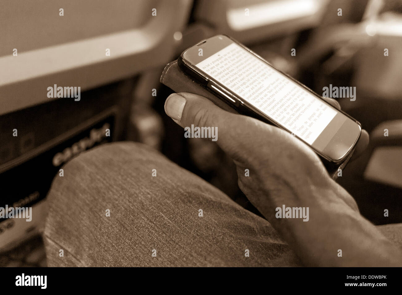 Lecture ebook sur smartphone pendant un vol. Banque D'Images