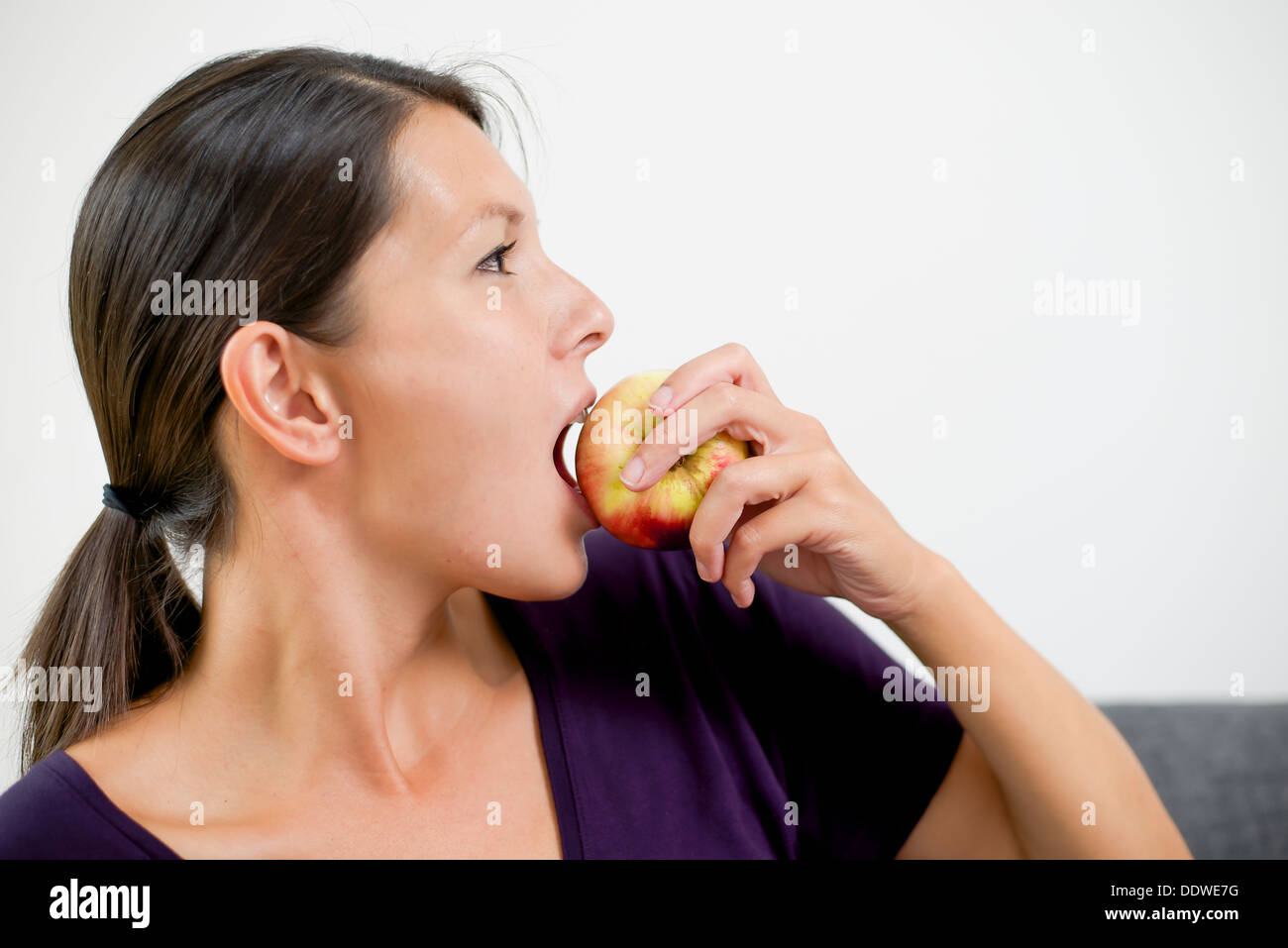 Femme frustratedSide est de voir une belle jeune femme mordre dans une pomme rouge juteux frais comme elle suit un régime alimentaire sain et Banque D'Images