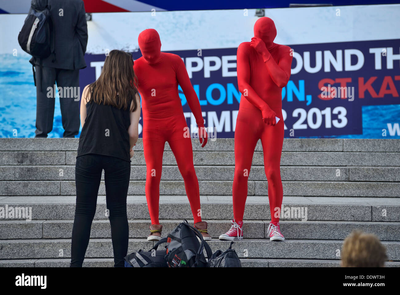 Des artistes en costumes rouges défilent devant le public Banque D'Images