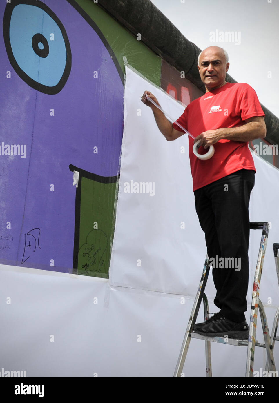 Peintre et président de l'initiative d'artistes East Side Gallery Kani Alavi travaille sur la East Side Gallery à Berlin, Allemagne, 08 septembre 2013. L'Artists' initiative vise à attirer l'attention sur le développement du site avec un couvrant l'action. Photo : OLIVER MEHLIS Banque D'Images