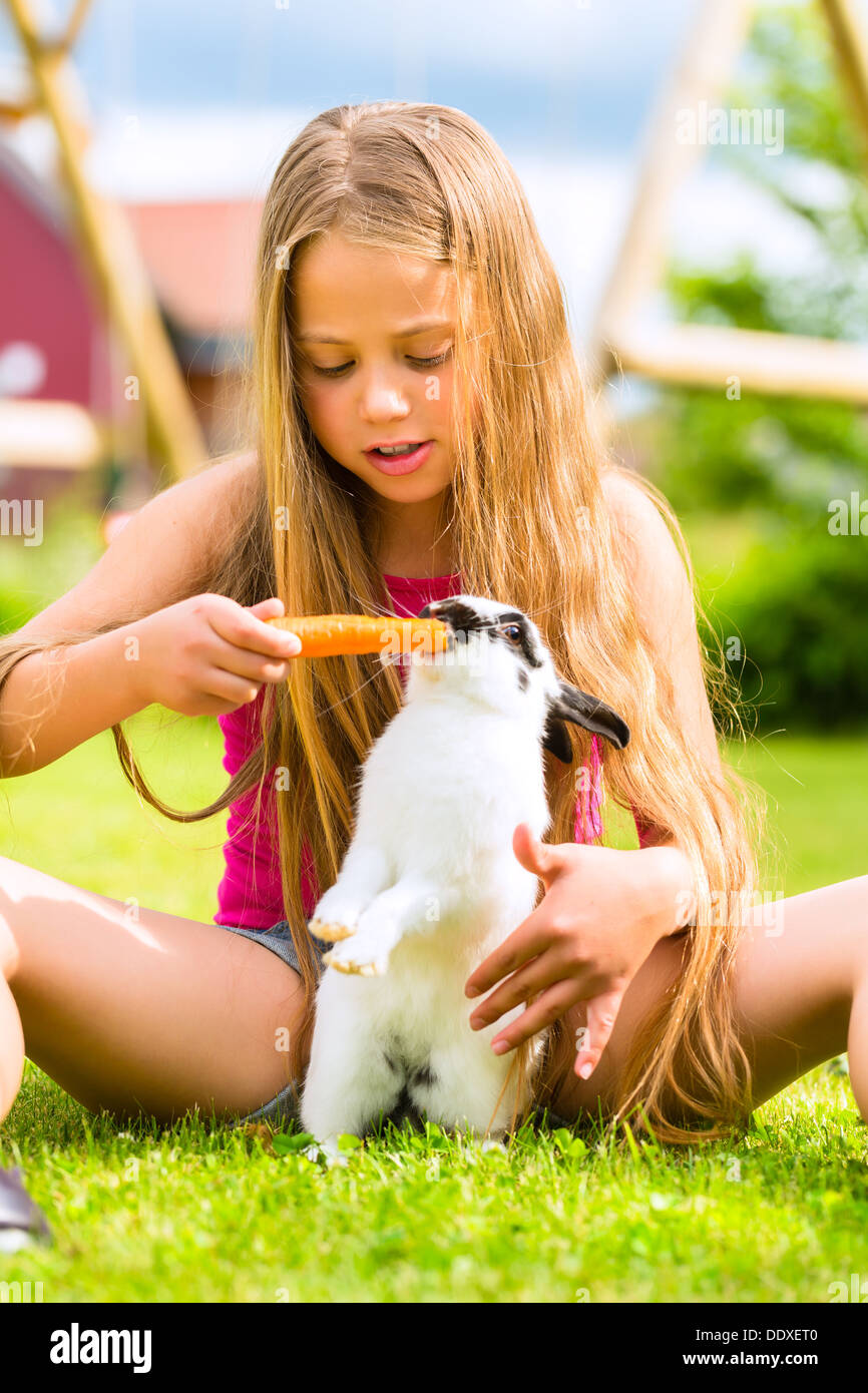 Happy Girl ou la fille avec son lapin ou bunny pet à la maison dans le jardin Banque D'Images