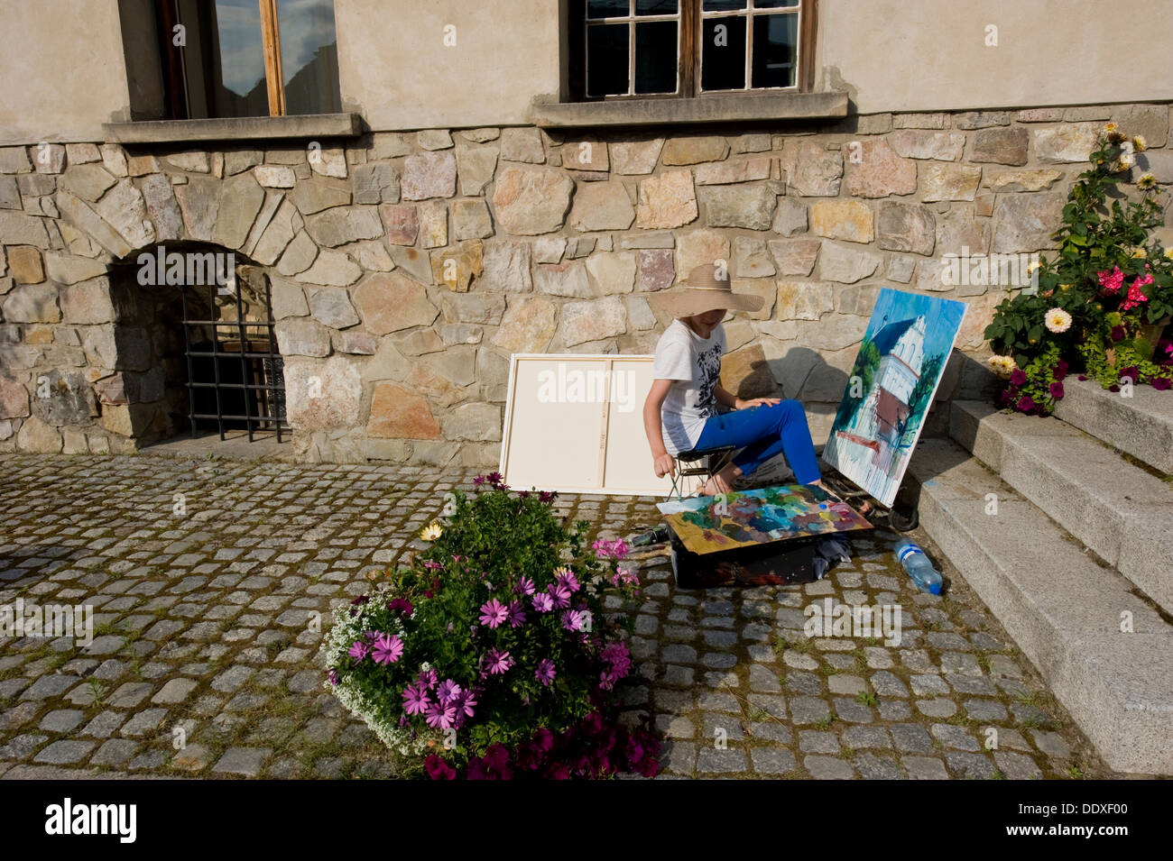 Une femme peintre travaillant à l'air libre sur une rue de Kazimierz Dolny. Banque D'Images