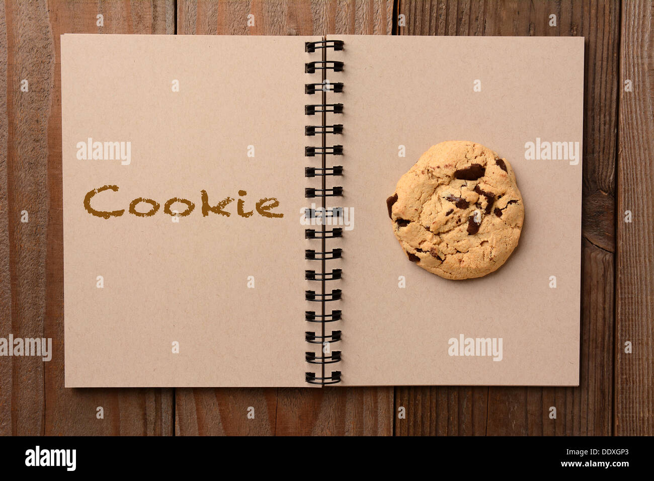 Un grand biscuit aux brisures de chocolat sur la page vierge d'un ordinateur portable. La page opposée a le mot Cookie précisées. Banque D'Images