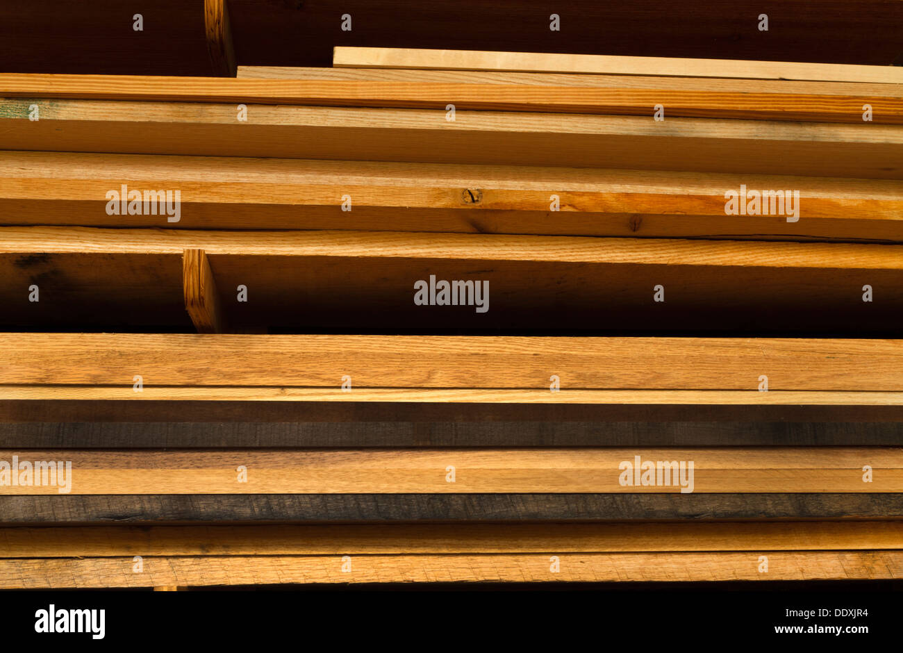 Divers conseils de bois empilés sur des étagères dans un atelier de travail du bois. La plupart des bois est bois de chêne à différents stades du vieillissement Banque D'Images