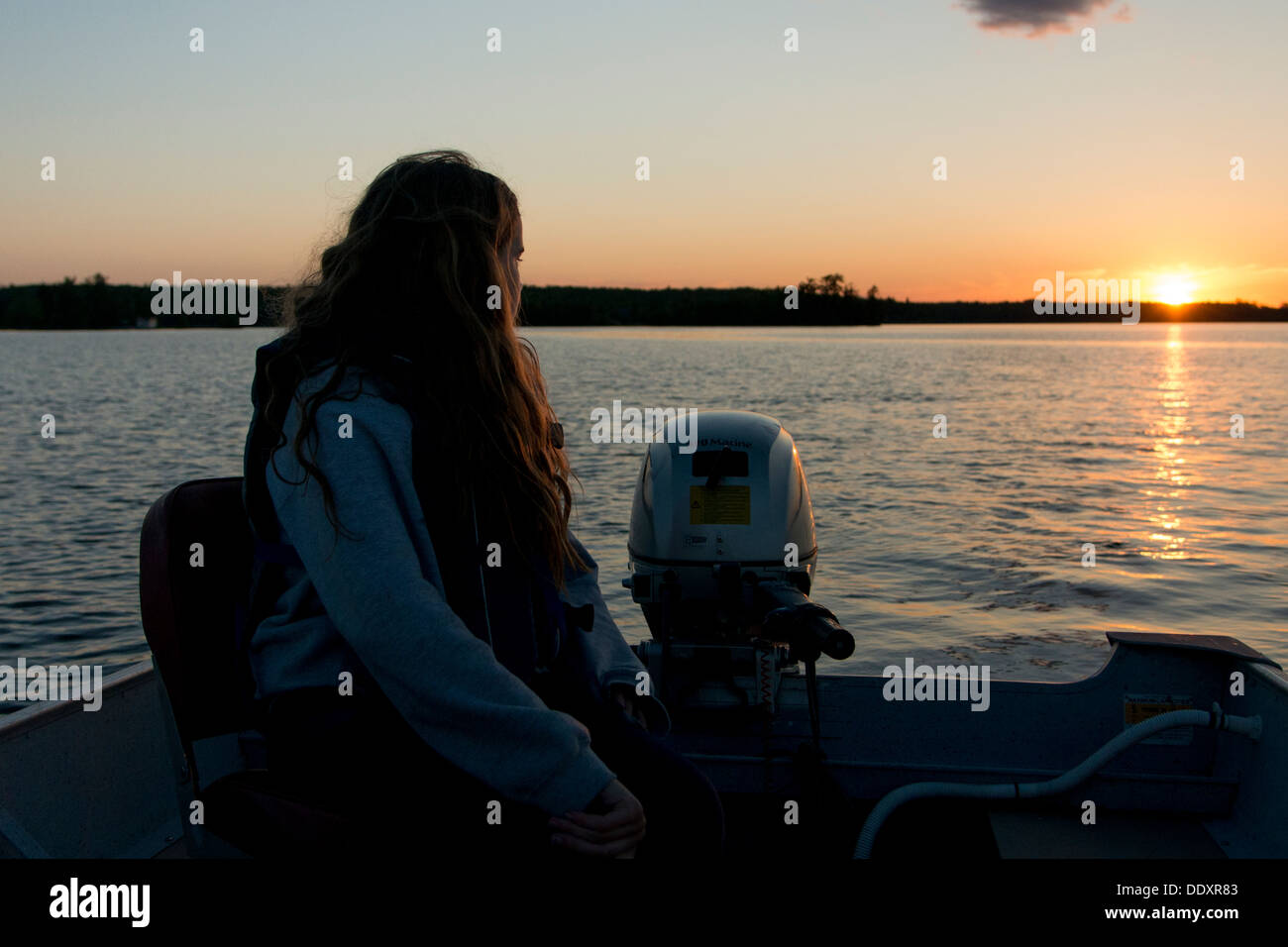 Fille assise sur un bateau dans le lac au coucher du soleil, le lac des Bois, Keewatin (Ontario), Canada Banque D'Images