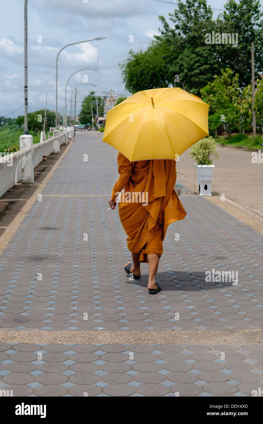 Monk walking sur la promenade avec un parapluie et une cigarette, Nong Khai, Thaïlande, Asie Banque D'Images