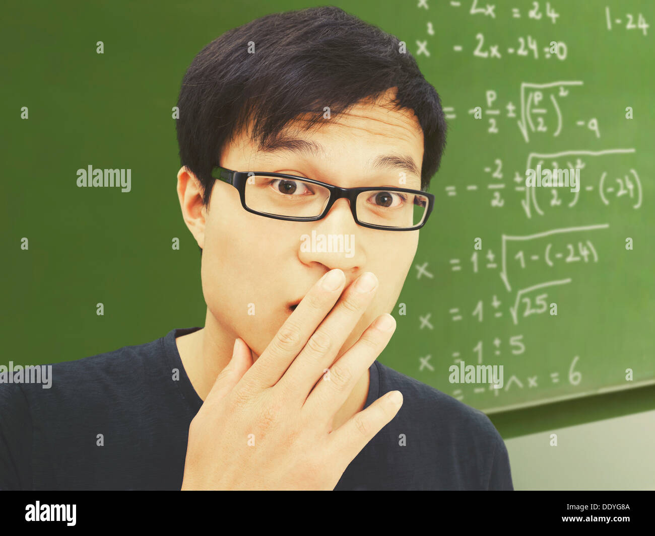 Jeune homme, Asiatique, étudiant à lunettes, devant un tableau noir avec des équations mathématiques, surpris, perplexe Banque D'Images