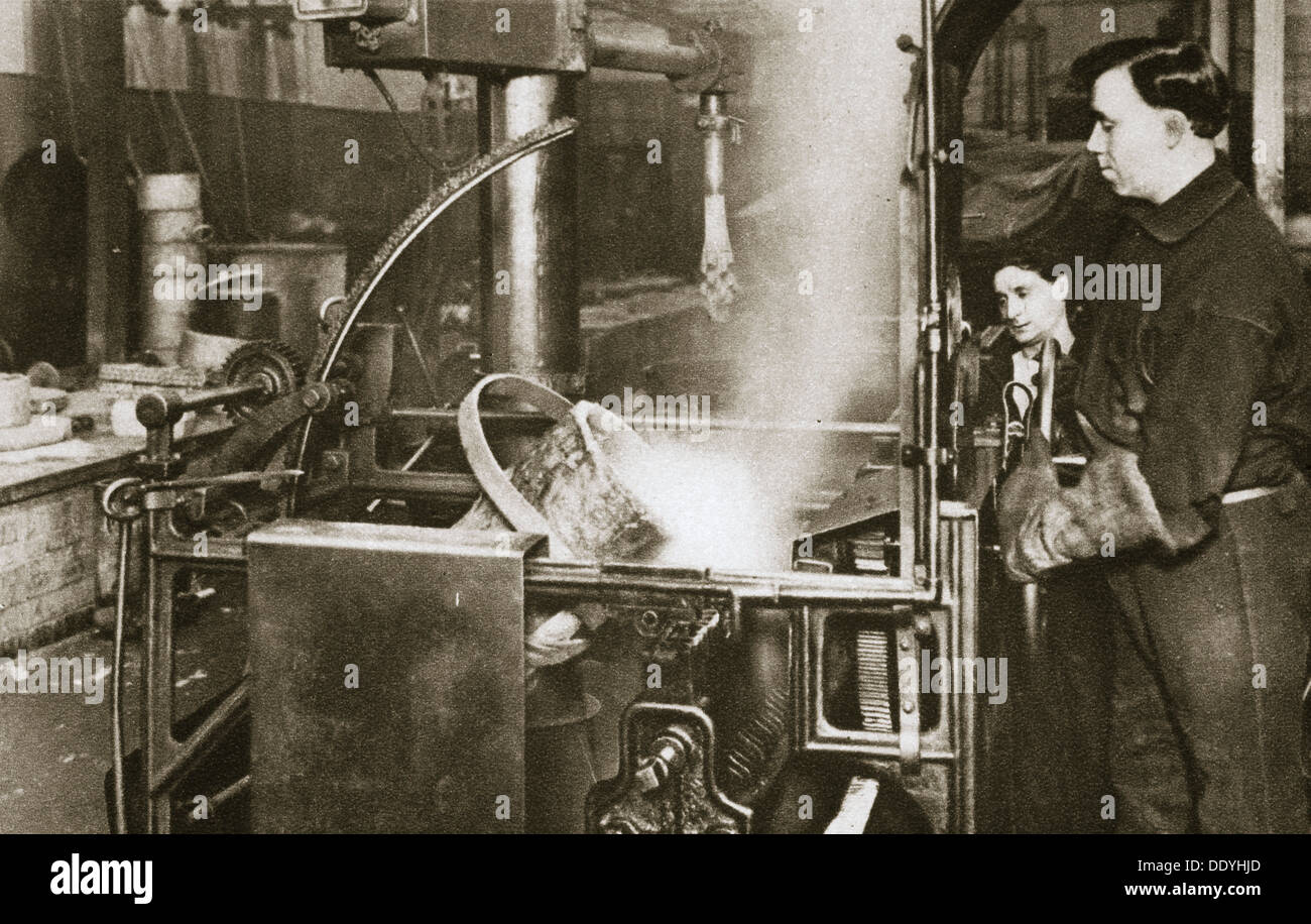 Faire de l'argent ; descente d'un pot de métal liquide dans une machine, 20e siècle. Artiste : Inconnu Banque D'Images