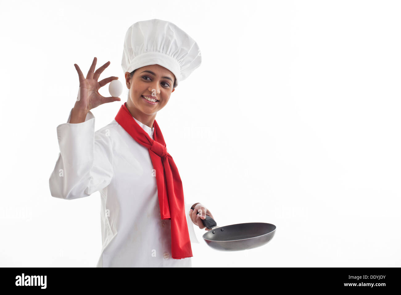 Happy female chef holding un oeuf et poêle isolé sur fond blanc Banque D'Images