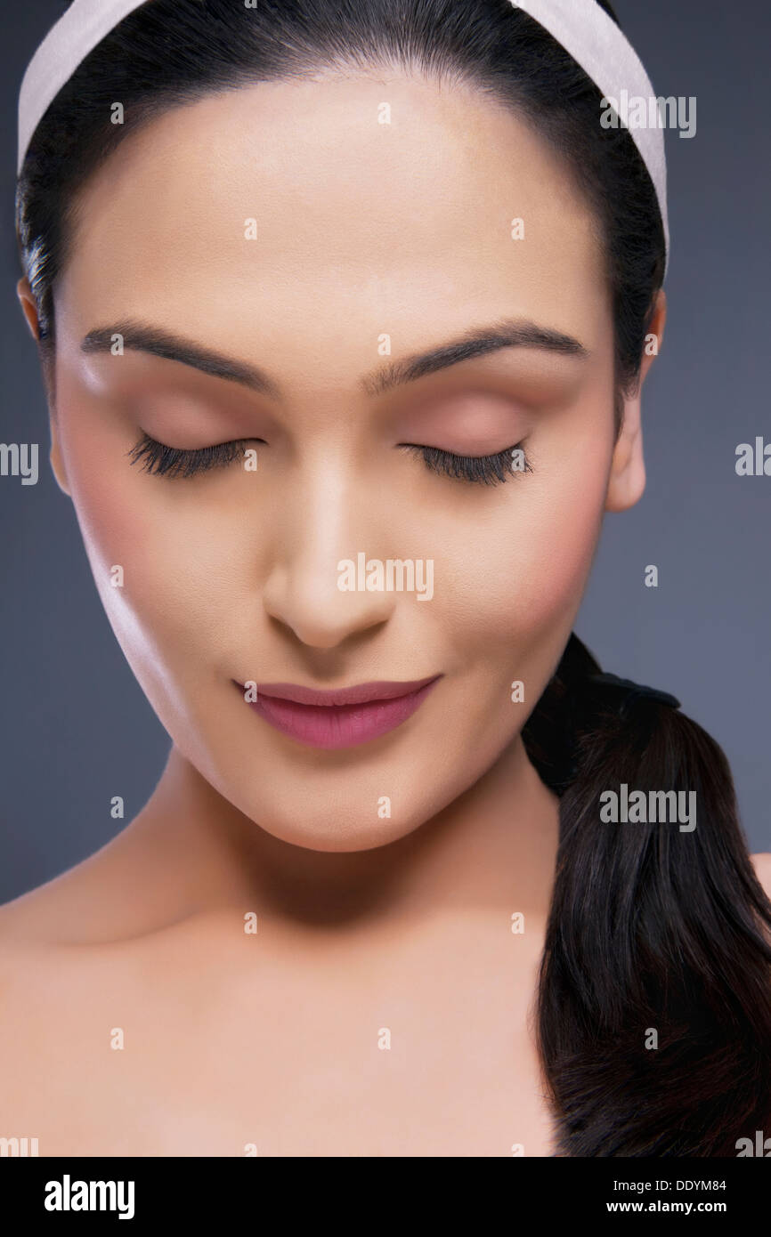 Head shot of belle femme calme avec les yeux fermés au cours de l'arrière-plan de couleur Banque D'Images