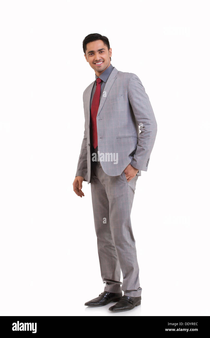 Portrait of young businessman with hand in pocket standing against white background Banque D'Images