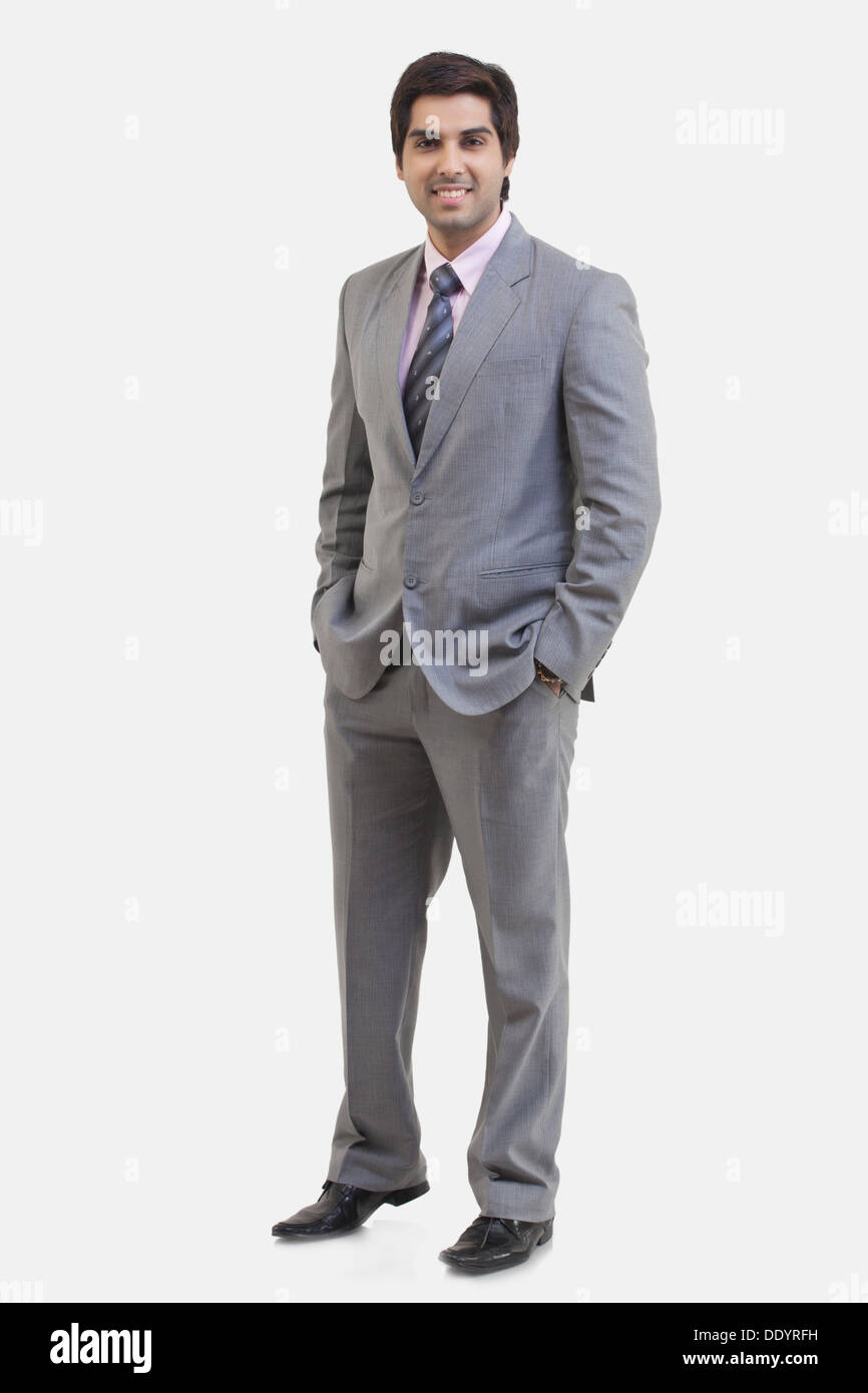 Full Length portrait of young businessman with hands in pockets standing against white background Banque D'Images