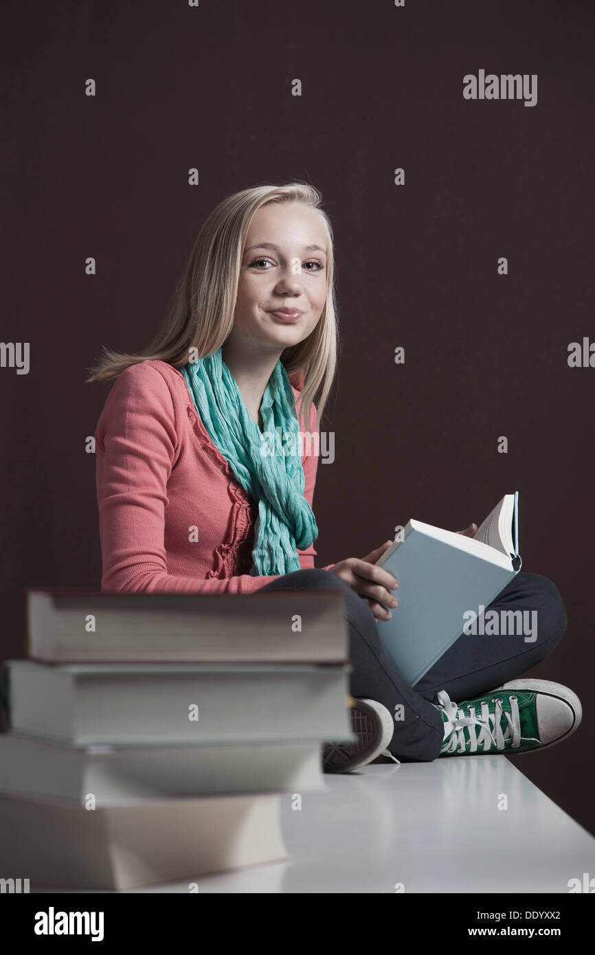 Teenage girl reading a book, avec une pile de livres à l'avant Banque D'Images