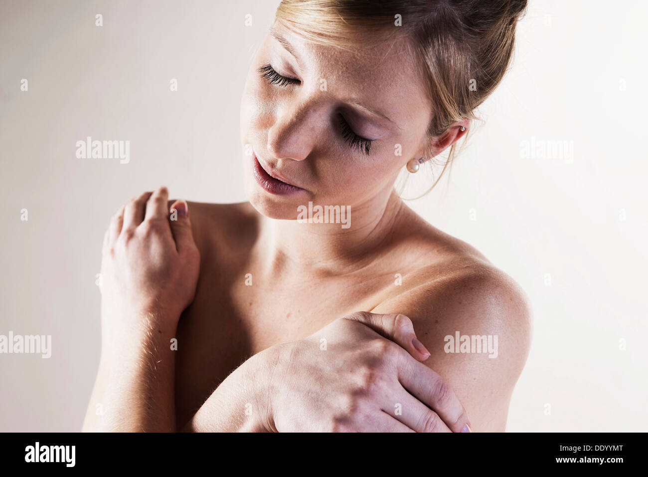 Jeune femme debout, nu, les bras croisés et les yeux fermés Banque D'Images