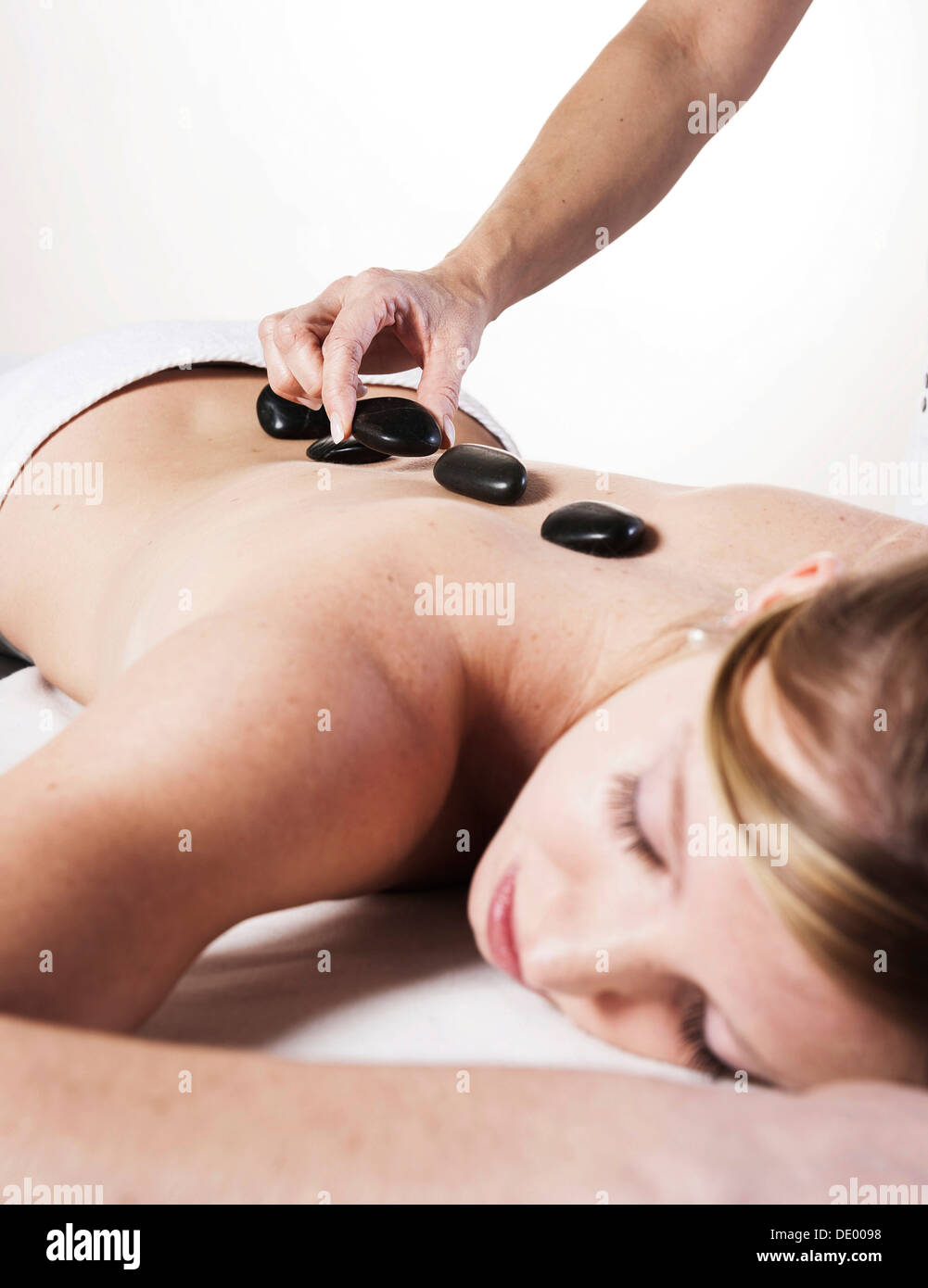 Jeune femme traitée avec pierres chaudes, massage aux pierres chaudes Banque D'Images