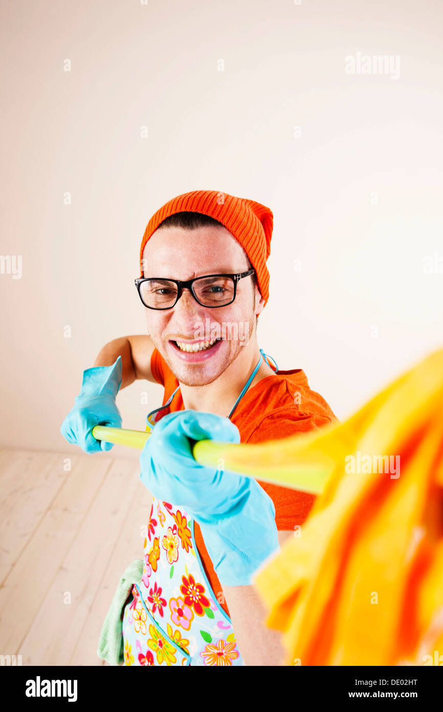 Jeune homme portant un tablier et gants de nettoyage avec une vadrouille nettoyage Banque D'Images
