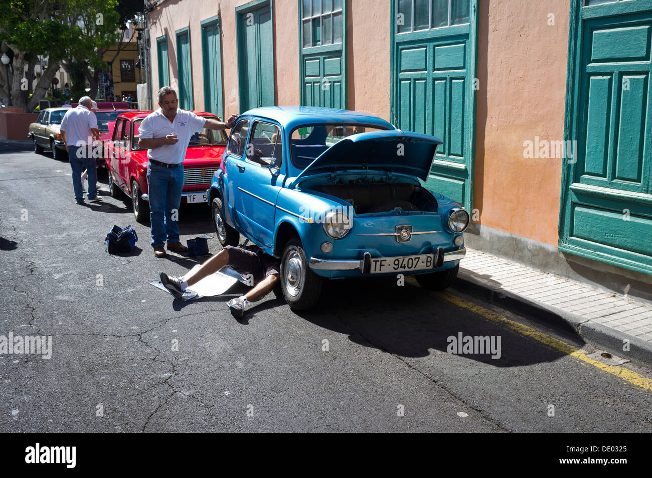 Seat 600 vintage car ventilées avec homme étendu sous les réparations exigées pendant qu'un autre regarde sur. Banque D'Images